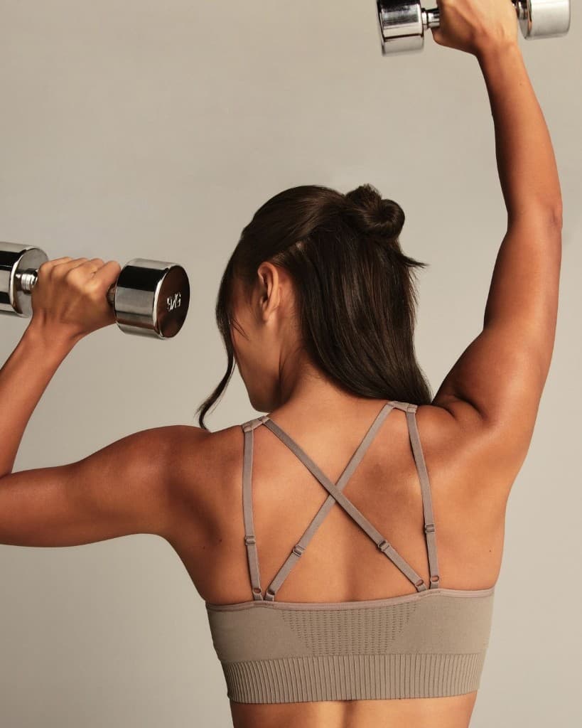 A woman pressing dumbbells overhead
